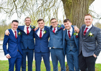 Groom and his groomsmen smiling at the lenses